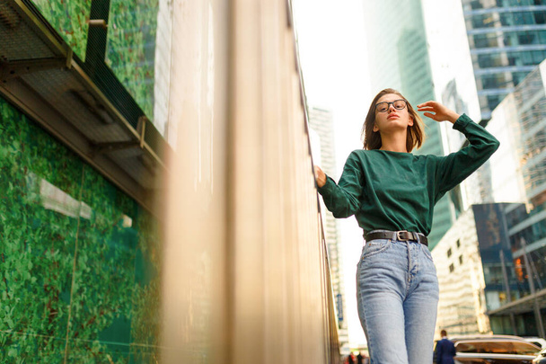 Retrato de uma menina hipster com penteado curto, olhando para longe posando na rua urbana, em edifícios modernos fundo. - Foto, Imagem
