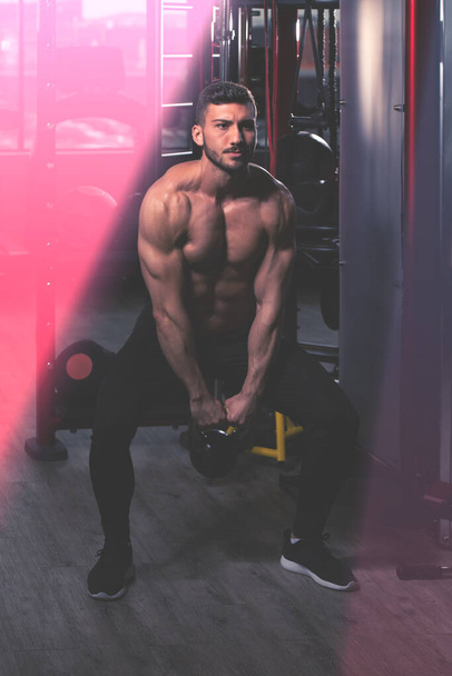 Man Exercising With Kettle Bell And Flexing Muscles - Muscular Athletic Bodybuilder Fitness Model Exercises - Fotografie, Obrázek