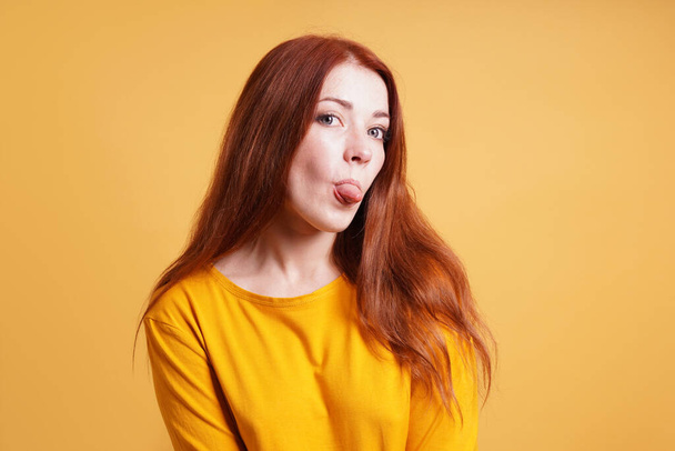 freche junge Frau streckt die Zunge heraus - Foto, Bild