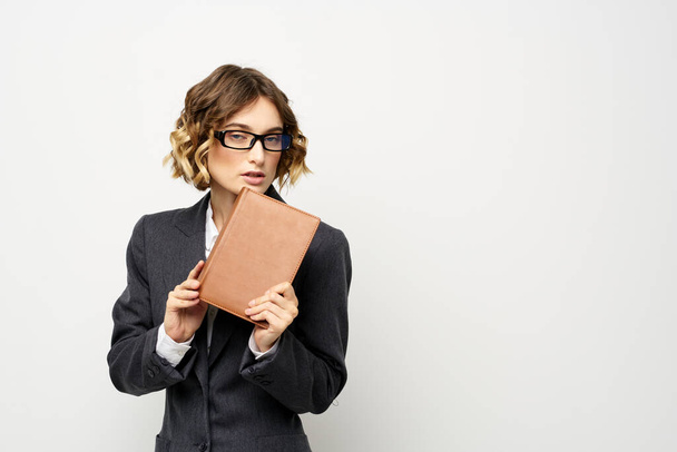 Biznes kobieta z notatnikiem i okulary pracy lekkie tło przycięte widok garnitur modelu. - Zdjęcie, obraz