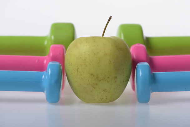 Apple fruit between pink, blue and green barbells in pattern - Foto, immagini