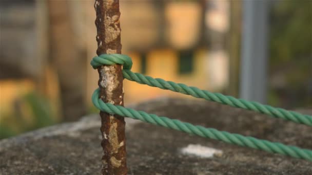 Een touw is vastgebonden in een knoop rond een hek paal, touw vastgebonden Hitch knopen op een roestige ijzeren paal geïsoleerd van de achtergrond. - Video