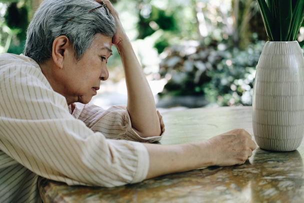 korosti masentunut väsynyt surullinen järkyttynyt aasialainen vanha aasialainen vanhempi vanhempi nainen istuu puutarhassa. - Valokuva, kuva