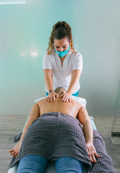 Фізіотерапевт дає масаж спини молодій жінці. Руки терапевта масажують спину жінки
. - Фото, зображення