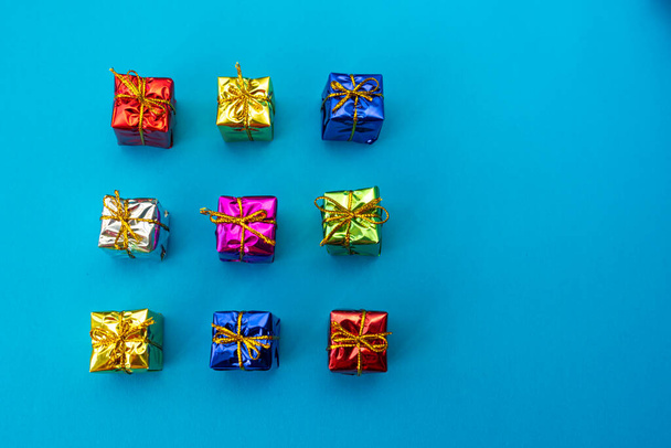 Top view of multicolored bright holiday gift boxes on a blue background. Copy space. - Фото, изображение