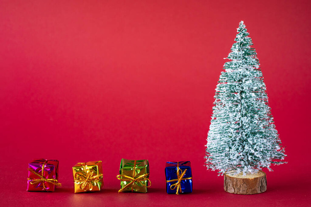 Fondo de vacaciones de Navidad. Árbol de Navidad cubierto de nieve y brillantes cajas multicolores con regalos. Copiar espacio. - Foto, Imagen