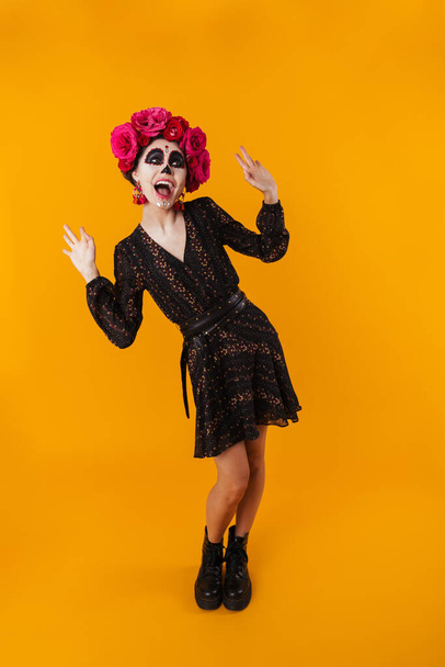 Laughing girl in halloween makeup posing on camera isolated over yellow background - Foto, imagen