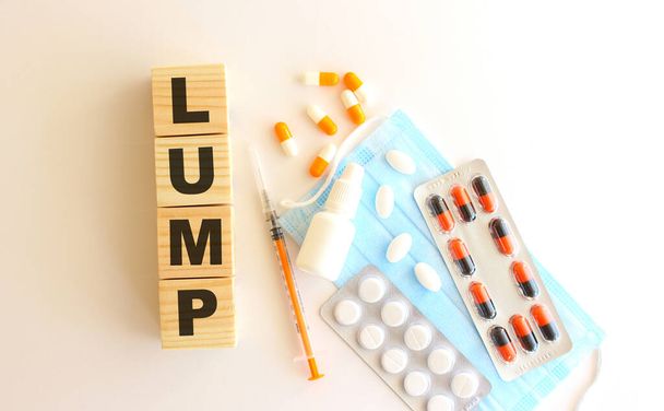 Слово LUMP складається з дерев'яних кубиків на білому тлі з медичними препаратами та медичною маскою.. - Фото, зображення