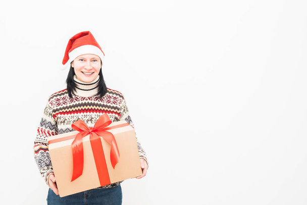 Woman courier in santa hat and christmas sweater holding gift on light background. - Фото, изображение