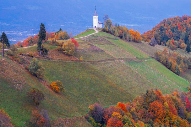 Kranj város közelében Jamnik templom domboldalon őszi színek naplementekor Szlovéniában, Európában - Fotó, kép
