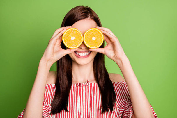 Closeup headshot photo of cute lovely young girl shiny smiling hold two oranges specs having fun wear striped white red blouse uncovered shoulders bright green color background - Fotografie, Obrázek