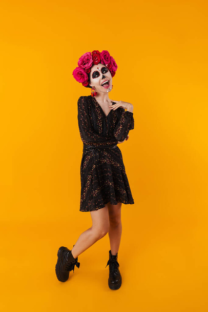 Laughing girl in halloween makeup posing on camera isolated over yellow background - Foto, Imagem