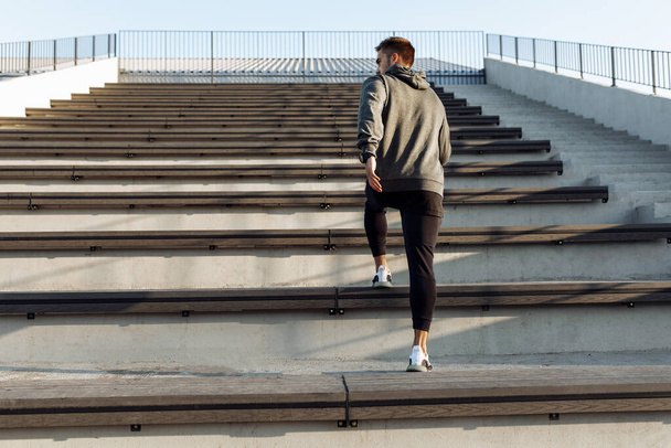 Sporty young man, in sportswear, jogging while training outdoors on the city stairs, sport, healthy lifestyle - Photo, image