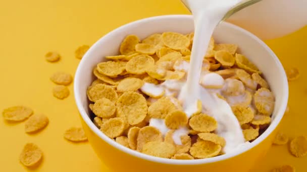 Leche vertiendo en un tazón de cereal de copos de maíz, vista superior - Metraje, vídeo