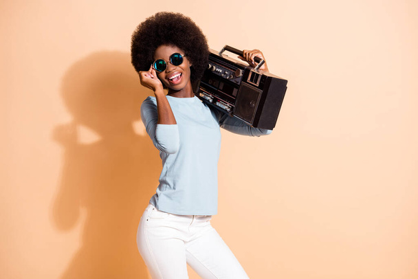 Photo portrait of african american girl holding boombox eyewear isolated on pastel beige colored background - Photo, Image