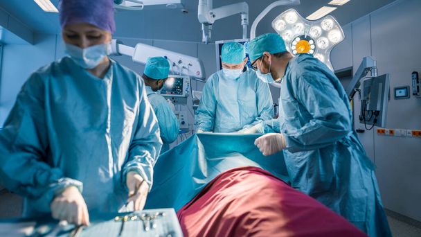 Diverse Team of Professional surgeon, Assistants and Nurses Performing Invasive Surgery on a Patient in the Hospital Operating Room. Surgeons Talk and Use Instruments. Real Modern Hospital with - Photo, image