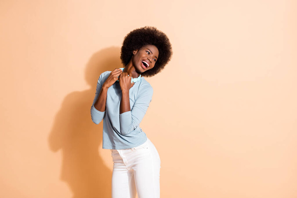 Photo portrait of black skinned girl holding cyan wireless headphones laughing isolated on pastel beige colored background - Φωτογραφία, εικόνα