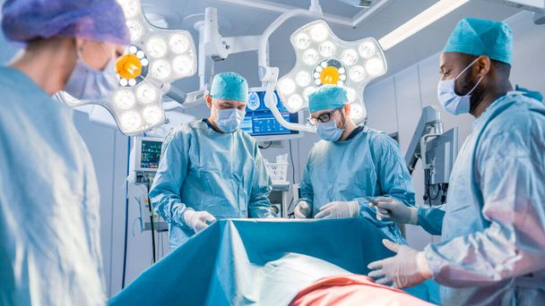 Diverse Team of Professional surgeon,  Assistants and Nurses Performing Invasive Surgery on a Patient in the Hospital Operating Room. Surgeons Have Active Discussion About to Saving Life of a Patient. - Foto, afbeelding