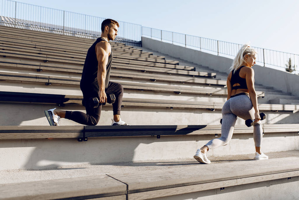 Stretching outdoors. Sportive young couple in sportswear doing stretching exercises together on the stairs in the city, healthy lifestyle, sports - Φωτογραφία, εικόνα