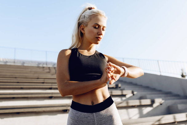 Young sportive woman checking progress on smart watch, runner looking at heart rate monitor smart watch outdoors, sport, healthy lifestyle - Foto, Bild