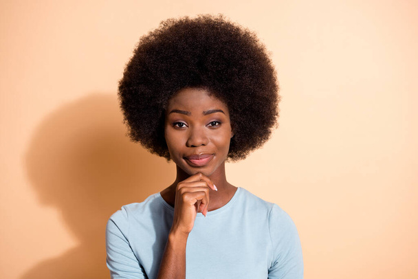 Photo portrait of successful african american woman touching chin with one finger isolated on pastel beige colored background - Φωτογραφία, εικόνα