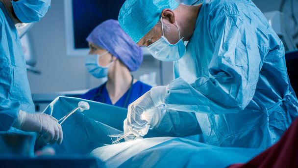 In the Hospital Operating Room Diverse Team of Professional Surgeons and Nurses Suture Wound after Successful Surgery. - 写真・画像