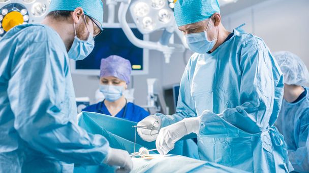Diverse Team of Professional surgeon, Assistants and Nurses Performing Invasive Surgery on a Patient in the Hospital Operating Room. Surgeons Talk and Use Instruments. Real Modern Hospital with - Photo, Image