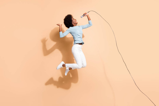 Photo portrait of excited african american woman singing holding mic in one hand in air isolated on pastel beige colored background - Φωτογραφία, εικόνα