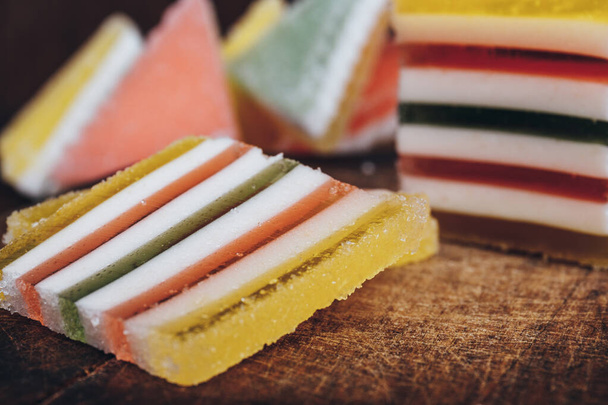 Sliced multicolored striped marmalade on wooden table. Colorful jelly candy close-up. - Photo, Image