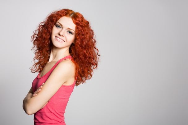 Smiling redhead girl on a background of gray wall - Foto, imagen