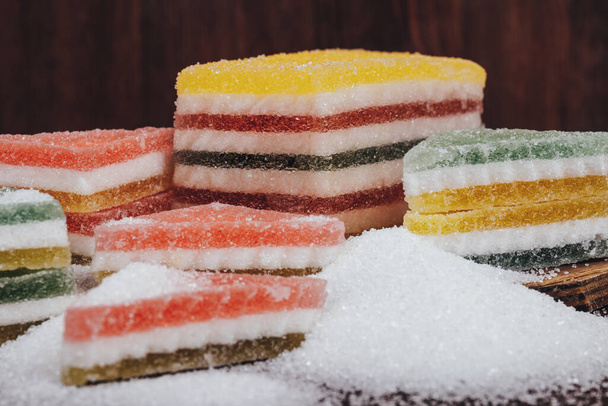Multi-colored marmalade jelly candy's. Heap of triangular and rectangular marmalade candy covered with sugar on wooden background. - Zdjęcie, obraz