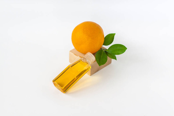 Orange oil for the body. Orange on a wooden pedestal on a white background. Organic SPA cosmetics with herbal ingredients. Cosmetology.  - Фото, изображение