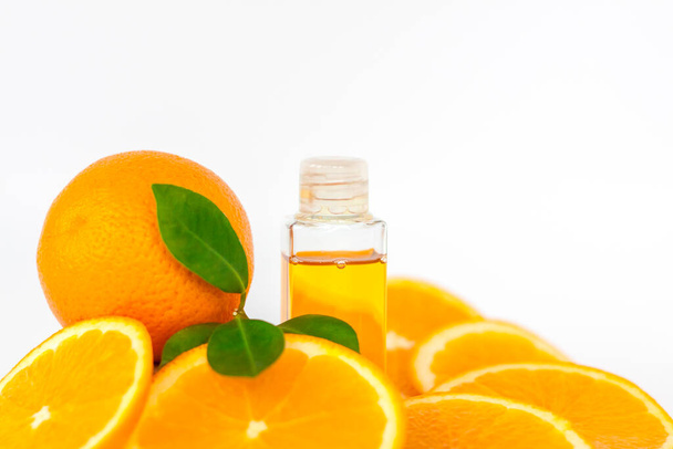 Appelsiiniöljyä keholle. Viipaloitu oranssi valkoisella pohjalla. Orgaaninen SPA kosmetiikka kasviperäisiä ainesosia. Kosmetologia. - Valokuva, kuva