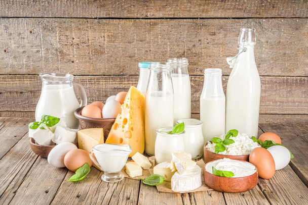 Conjunto de vários produtos lácteos frescos - leite, queijo cottage, queijo, ovos, iogurte, creme de leite, manteiga em fundo de madeira - Foto, Imagem