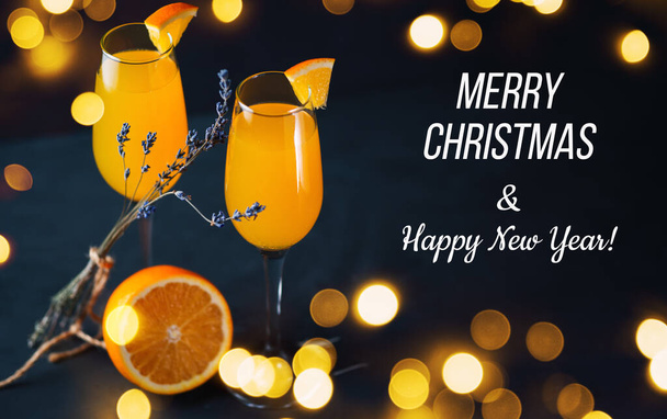 Mimosa-Cocktail auf dunklem Hintergrund mit Baque Girlanden, frohen Weihnachtsgrüßen und einem guten Rutsch ins neue Jahr - Foto, Bild
