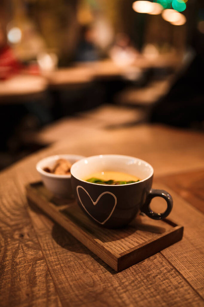 Serving cream soup in a cup with a cup of rusks on a wooden tray. - Foto, afbeelding