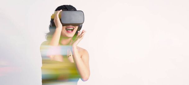 Aasian teini-ikäinen nainen yllään VR tai Virtual Reality kuulokkeet ja kirjoita digitaalisen simulaation maailmaan oppimiseen ja matkustamiseen tai pelaamista ja enemmän. Studio ampui valkoinen tausta - Valokuva, kuva