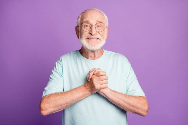 Photo of funny old beard man putting hands together wear light blue t-shirt isolated on purple color background - Valokuva, kuva