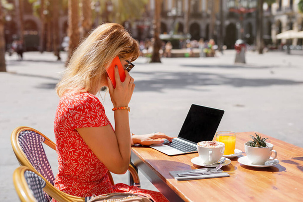 Geschäftsfrau arbeitet mit Laptop und telefoniert im Café - Foto, Bild
