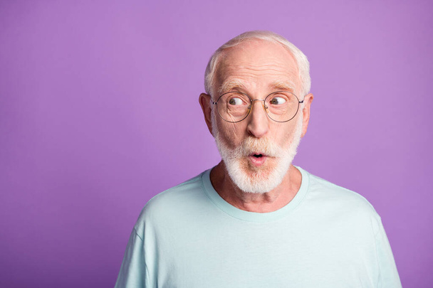 Portrait of surprised pensioner wear light blue t-shirt glasses open mouth empty space isolated on violet color background - Foto, Imagem