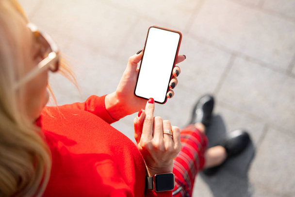 Жінка використовує мобільний телефон з порожнім білим макетним екраном, вид зверху
 - Фото, зображення