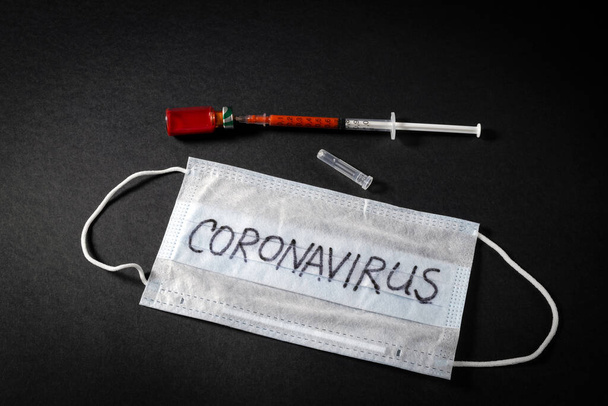 a syringe with blood and an ampoule with the result of a blood test for a new rapidly spreading nCOV - 2020 coronavirus originating from Wuhan, China on a black background - Zdjęcie, obraz