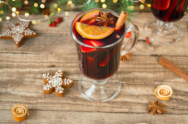 Top view hristmas hot mulled wine with carnation, cinnamon, cardamom and anise on wooden background with Christmas decorations. New Year drinks. - Foto, afbeelding