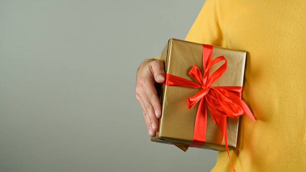 Egy férfi kezében egy piros masnis ajándékdobozzal. Kiváló minőségű fénykép - Fotó, kép