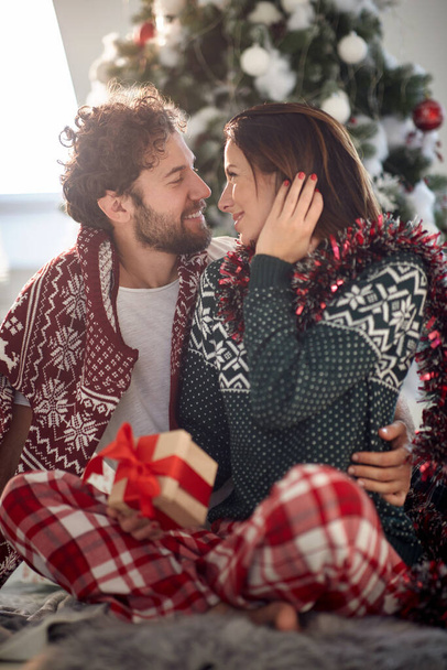 Cheerful couple sharing gifts on Chrismas morning at home - Фото, изображение