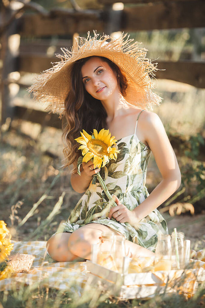 Attractive young lady with sunflower. Beautiful woman outdoors at summer. - Foto, immagini