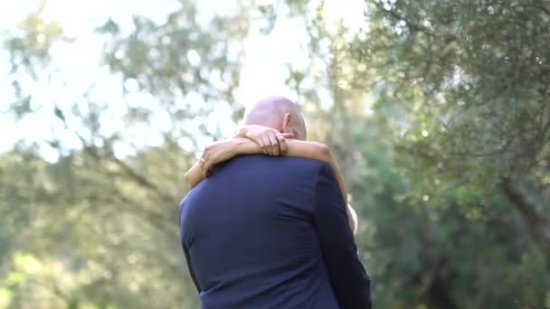 der Bräutigam und die Braut umarmen sich, die Braut wirft sanft ihre Arme um den Hals des Bräutigams - Filmmaterial, Video