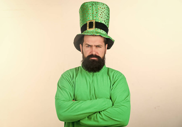 Being serious on saint patricks day. Hipster in leprechaun hat and costume keeping arms crossed. Irish man with beard wearing green. Bearded man celebrating saint patricks day. Bearded and brutal - Фото, изображение