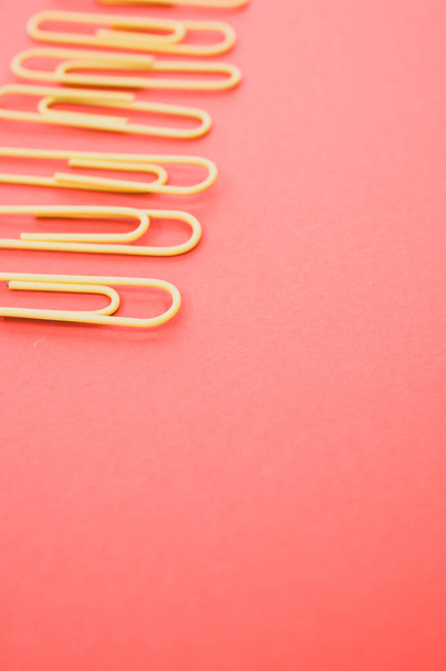 A vertical shot of multicolored paper clips on a piece of paper - Photo, image