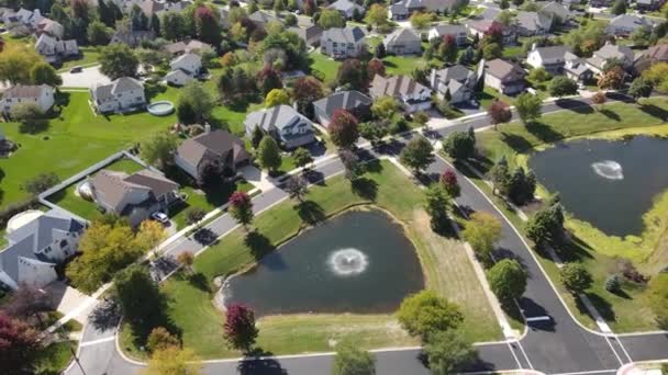 Vista aérea aérea de árvores coloridas de outono, casas residenciais e quintais com lagoa de drenagem ao longo da rua suburbana na área de Chicago. Centro-Oeste dos EUA. 4K - Filmagem, Vídeo